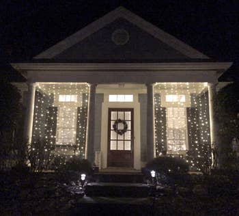 reviewer photo of two of the string light panels lit up between columns on their front porch