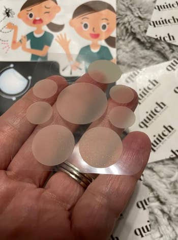 Hand holding assorted  sizes of translucent pimple patches, with packaging showing illustrations of a woman