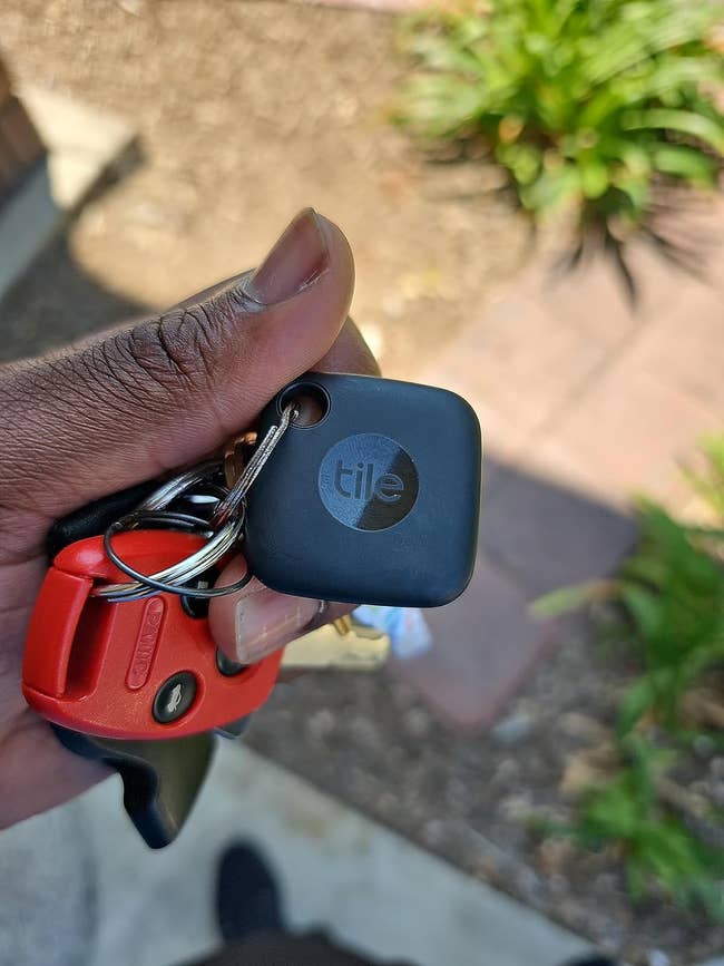 A reviewer holding their keychain with their keys and Tile Mate attached