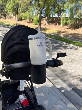 a stanley cup in a silicone cup holder attached to a stroller