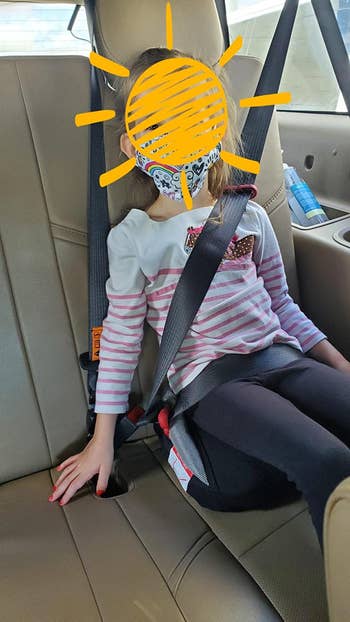 reviewer image of a child using the booster seat in a car