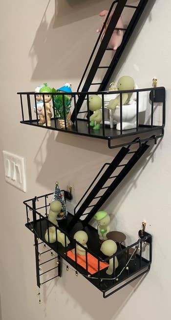 Wall-mounted zigzag support  with tiny  figurines and decorative items, including plants and a miniature tree, connected  a beige wall