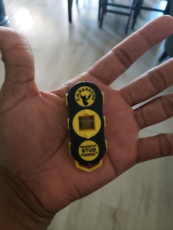 a stud finder in a reviewer's hand, it fits in their palm