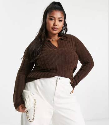 model wearing brown long-sleeve v-neck sweater tucked into white jeans