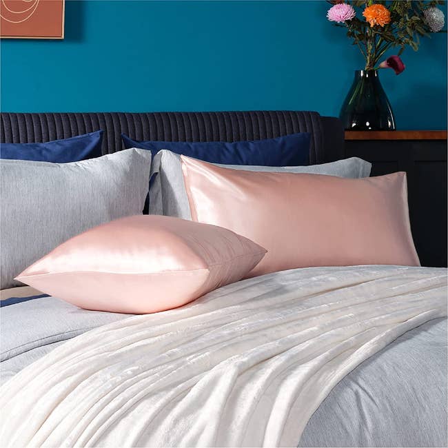 two pillows in pink satin cases on a bed