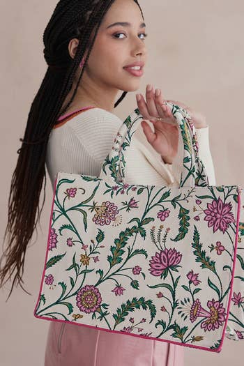 Woman posing with a floral embroidered tote bag, suitable for shopping, in a casual chic outfit