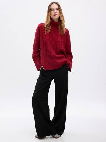 a model in a red turtleneck split hem cableknit sweater