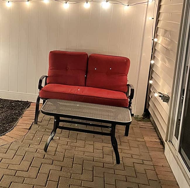 Reviewer image of black wrought iron loveseat with red cushions and black metal coffee table outside