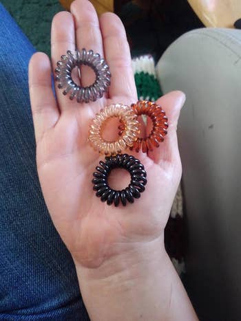 a reviewer holding four different colored spiral hair ties