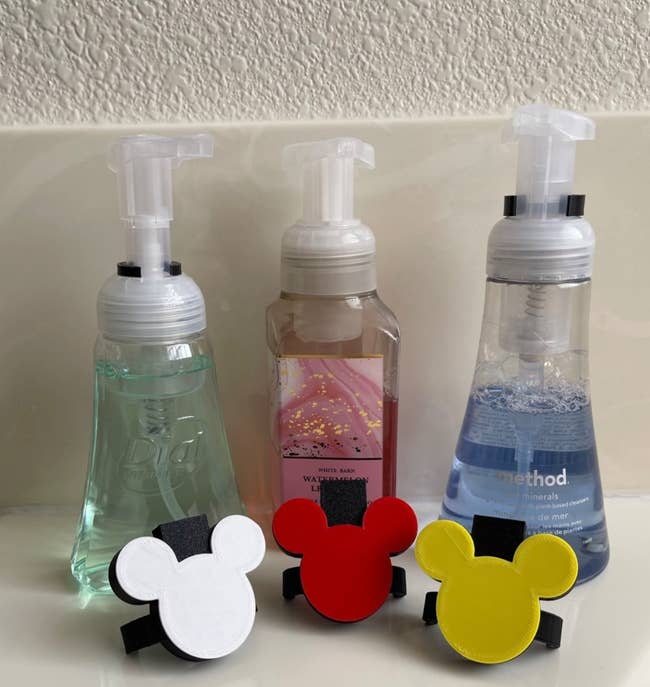 Three hand soap dispensers with Mickey Mouse-shaped holders