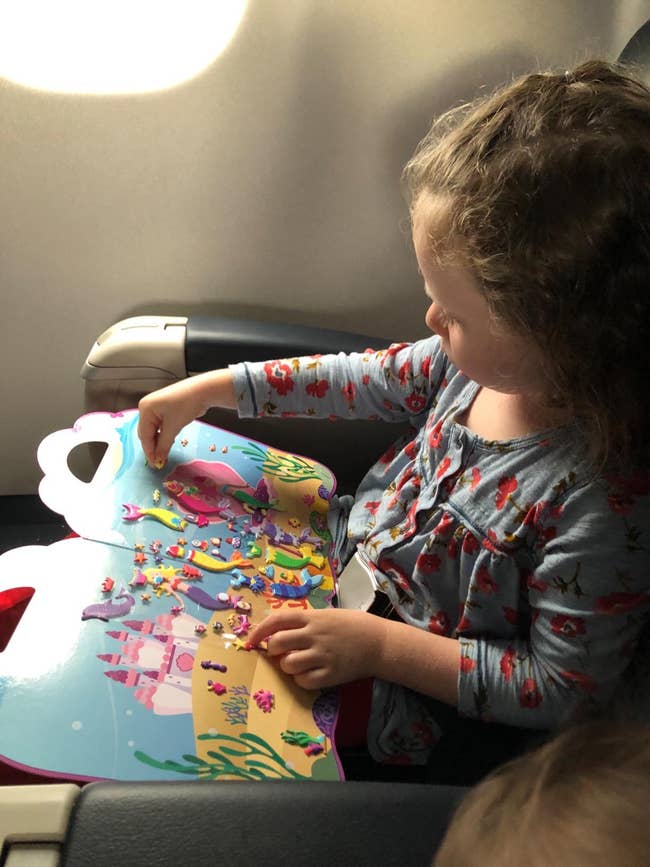 A child playing with the sticker book during a flight
