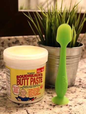 reviewer's green spatula next to a jar of butt paste