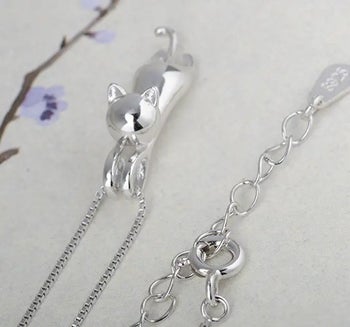 a close up of a shiny silver cat pendant