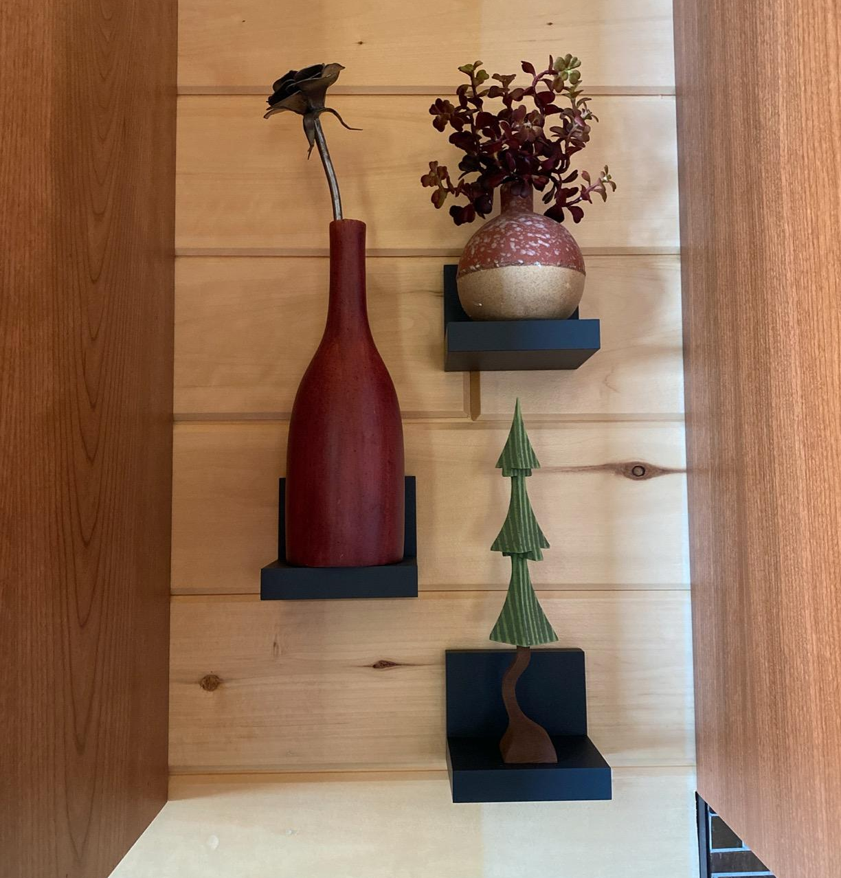 three of the black shelves on a wall holding decor
