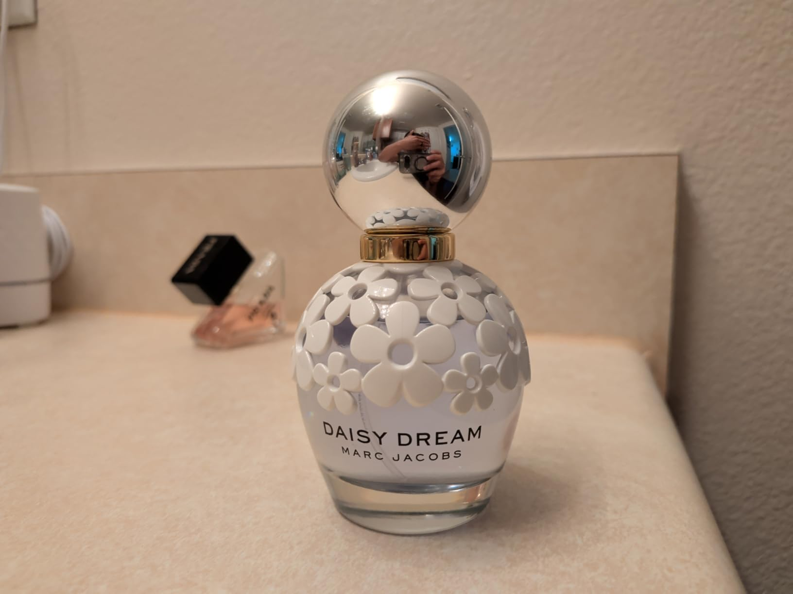 Daisy Dream by Marc Jacobs perfume vessel  with floral plan  connected  a countertop