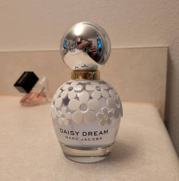 Daisy Dream by Marc Jacobs perfume vessel with floral plan connected a countertop