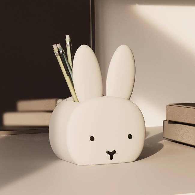 Cute bunny-shaped pen holder connected  a desk, holding pencils