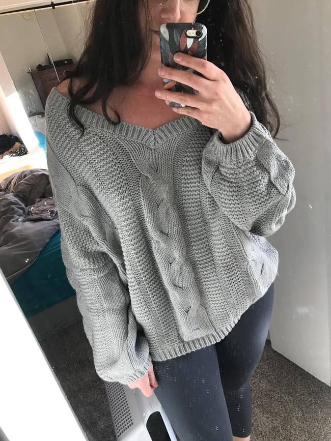 reviewer photo of them wearing a gray off-the-shoulder cable knit sweater
