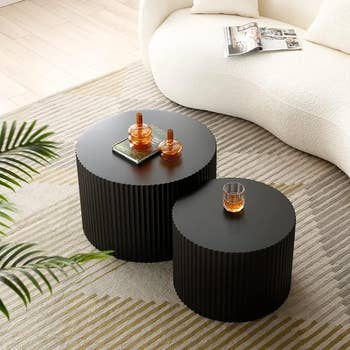 Two round, ribbed coffee tables with decor in a living space