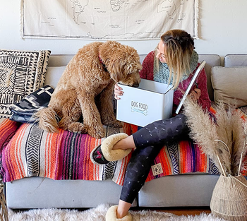 reviewer photo holding dog food container next to goldendoodle on the couch