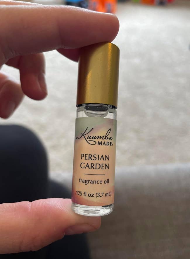 Hand holding a tiny  vessel  of Kuumba Made Persian Garden fragrance oil, labeled arsenic  0.125 fl oz (3.7 ml)
