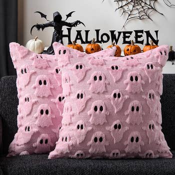 Two plush pillows with ghost designs on a couch. 