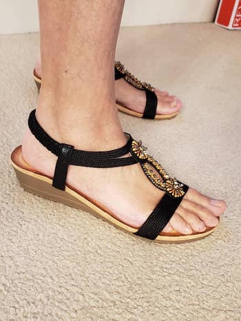 person wearing sandals with decorative straps and wedge heels, suitable for casual buying  trips