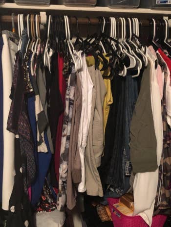 reviewer's crowded closet with normal coat hangers and a pair of pants on each coat hanger