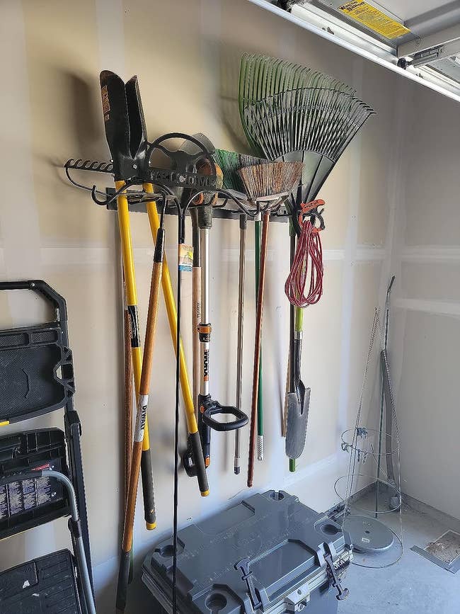 Reviewer photo of the mount holding many gardening tools in his garage