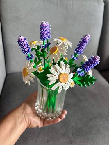 Artificial bouquet of daisies and lavender successful  a wide   vase, held successful  a hand, showcasing a decorative floral arrangement