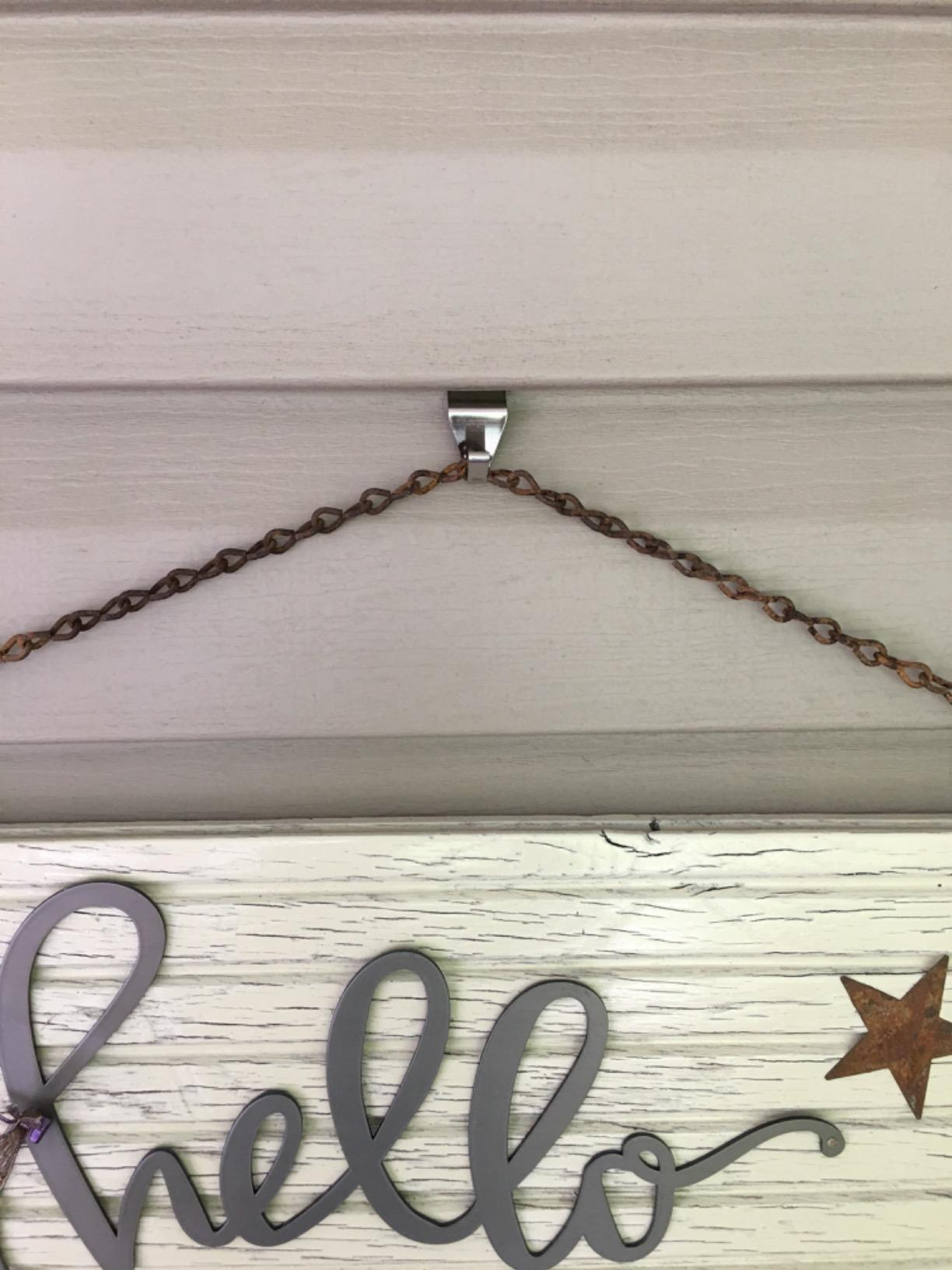 A decorative motion   hands from a hook installed connected  a house's siding 