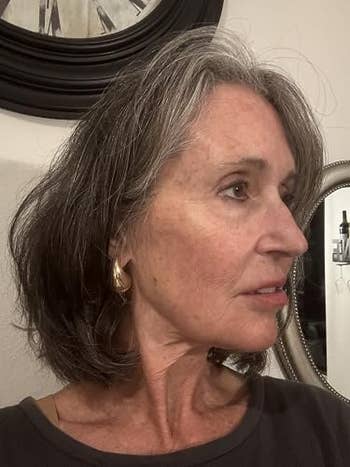 Person with short, layered hairsbreadth  wearing golden  hoop earrings, looking to the side