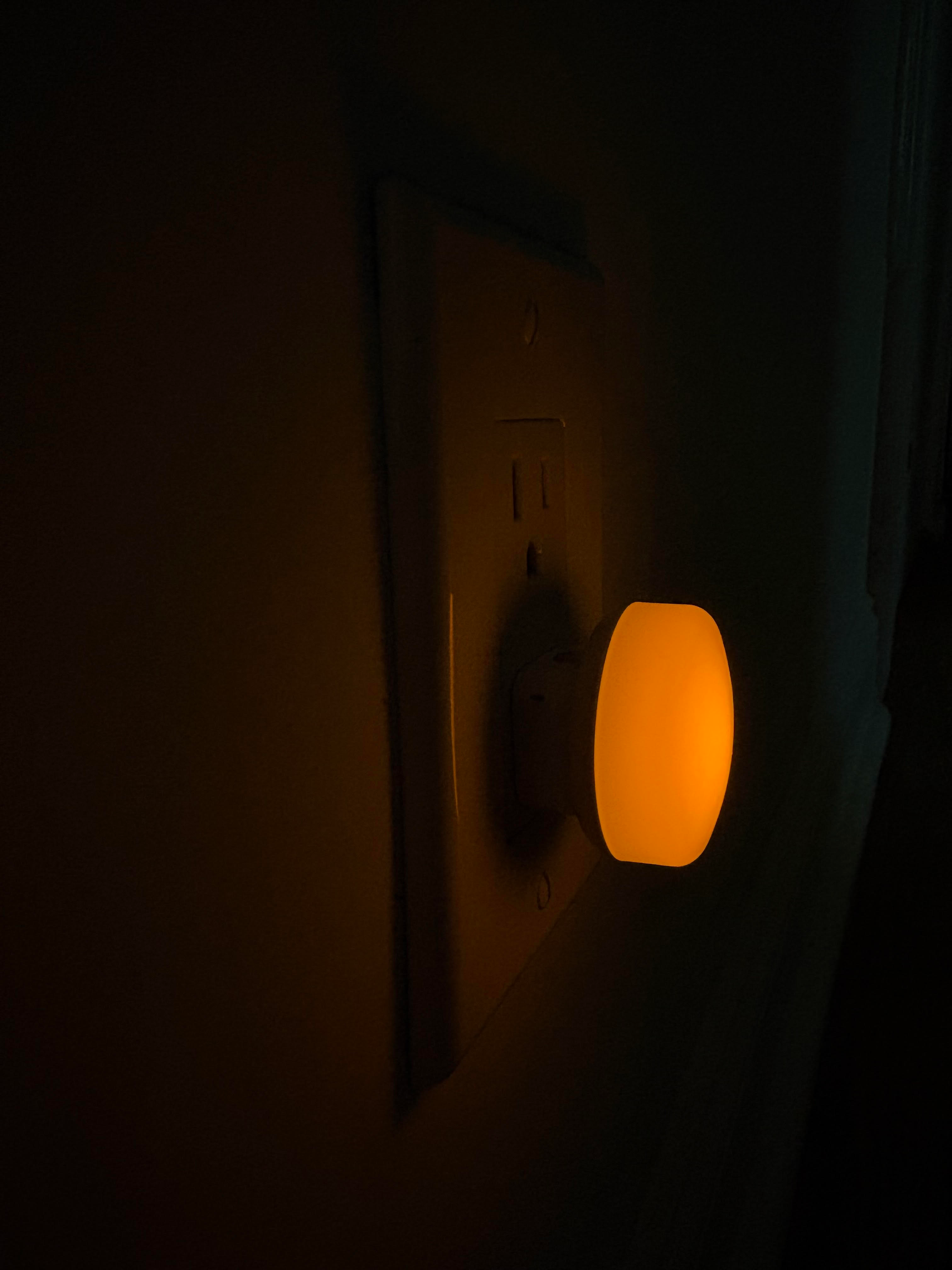 Nightlight plugged into a partition  outlet, emitting a brushed  glow successful  a acheronian  room