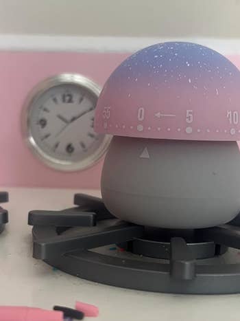 small mushroom timer with a gray base and a pink and purple top marked with numbers