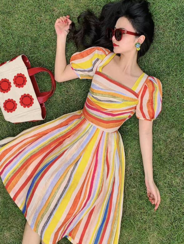 a model wearing the bright rainbow dress with lantern sleeves in the grass