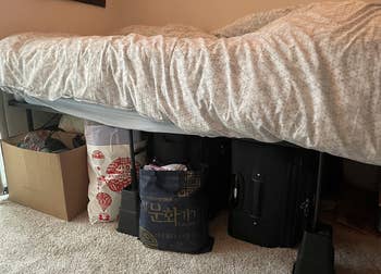a reviewer image of a bed on the risers with bags and boxes stored underneath