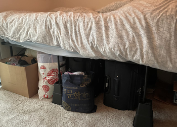 a reviewer image of a bed on the risers with bags and boxes stored underneath