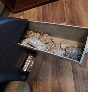 a reviewer photo of the litter box tray pulled out filled with clumps of litter 