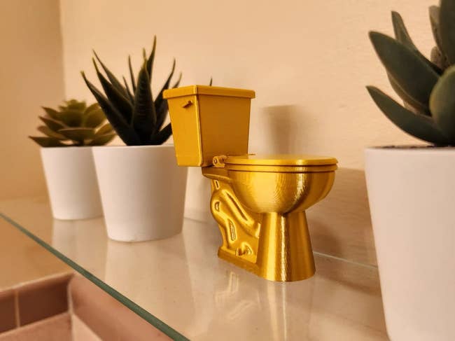 gold toilet shaped sculpture on shelf