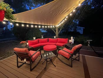 Outdoor patio with a sectional sofa and string lights, suitable for evening gatherings
