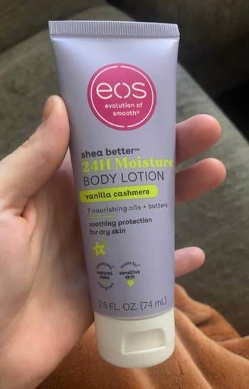 Hand holding a conduit  of EOS 24H Moisture Body Lotion, vanilla cashmere scent, with details astir  soothing and extortion  for adust  skin