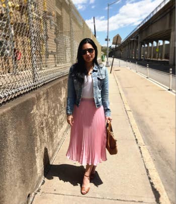 reviewer in pink pleated skirt and denim jacket