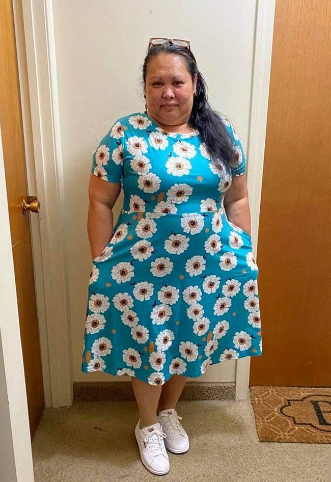 reviewer wearing short sleeve teal and white floral dress with their hands in the pockets