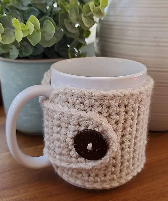 a mug wrapped in a beige mug sweater with a brown button