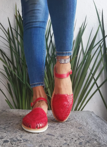 model wearing a pair of red Huarache sandals and jeans