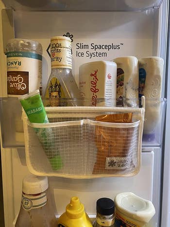 Mesh storage bag hanging in a fridge door filled with condiments and a milk bottle, providing organization and space optimization