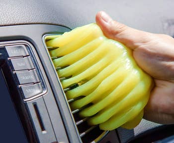 a model using the gel to clean a car air vent 