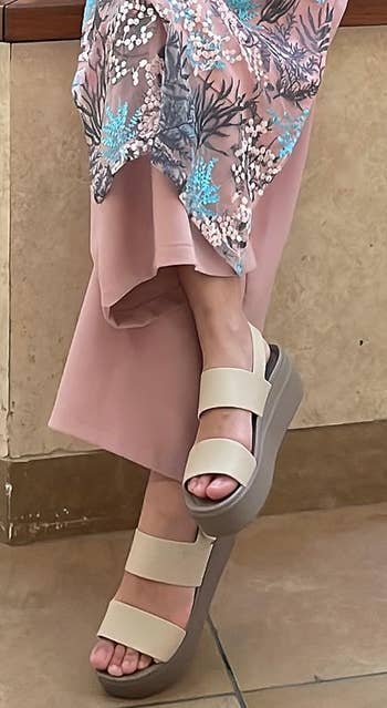 reviewer in beige platform sandals and a floral dress, focus on footwear style for shopping context