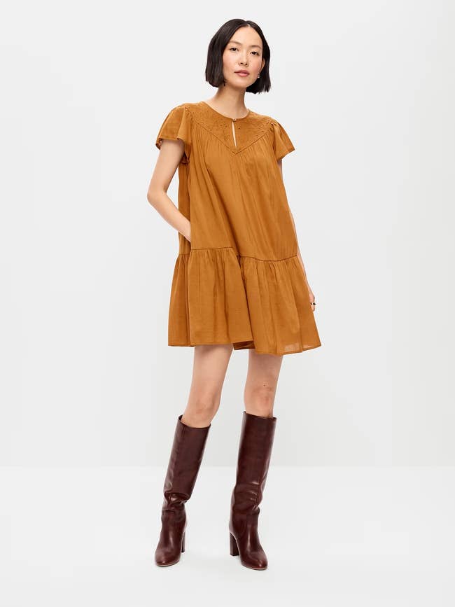 A idiosyncratic models a loose-fitting, short-sleeved formal paired with knee-high boots