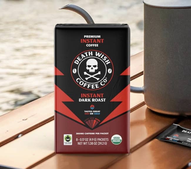 Death Wish Coffee's instant acheronian roast packet displayed adjacent to a metallic mug, highlighting its premium prime and USDA integrated certification